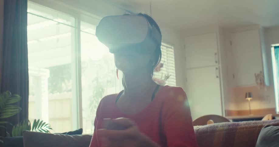 Close up of a young woman swinging her arms while playing a virtual reality game while sitting in a living room