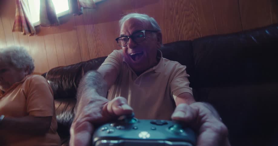 Elderly couple plays a video game while sitting in the living room during the daytime