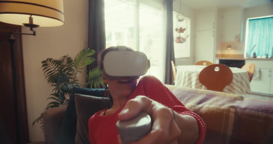 A woman is using a virtual reality headset and swinging a controller