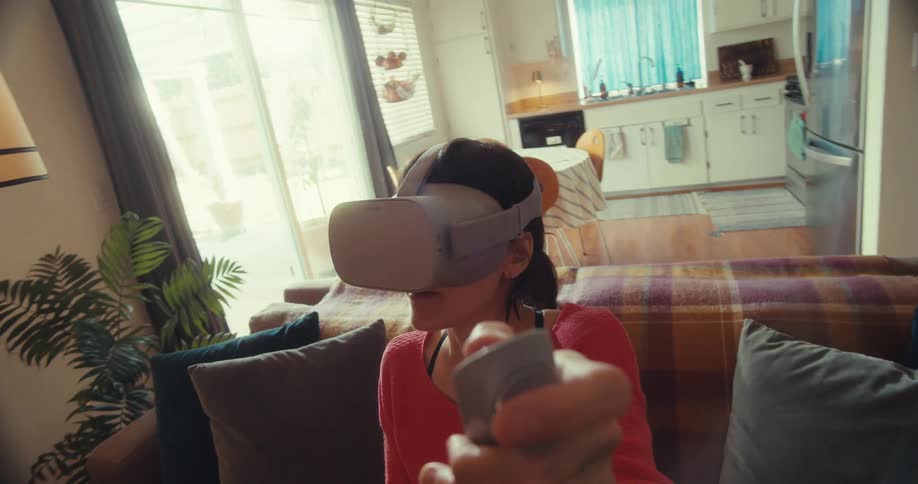 A girl uses a vr headset and controller while sitting on a couch at home