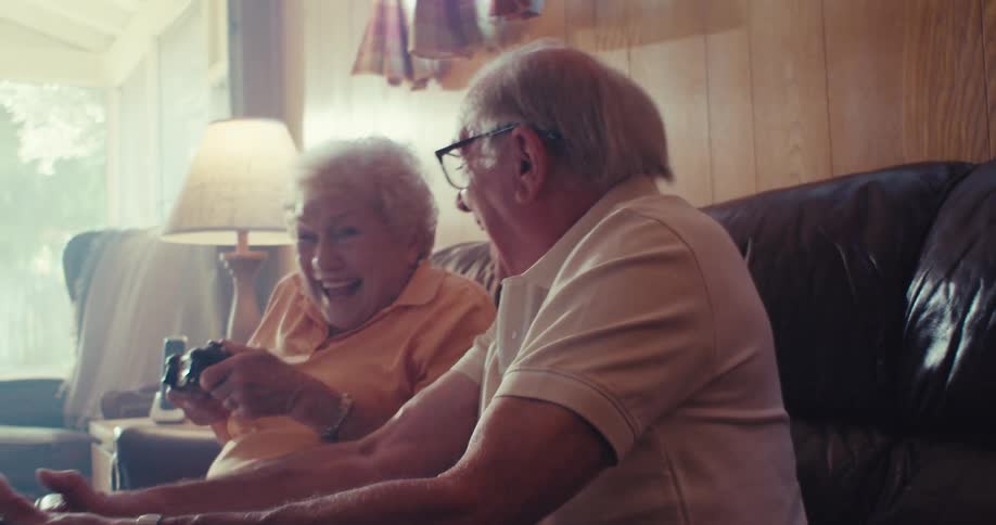 Elderly couple sitting playing video games and having fun