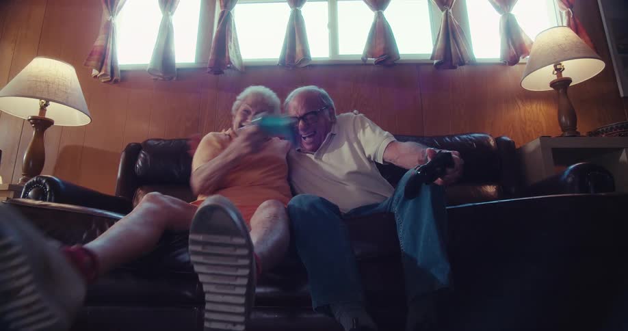 Elderly couple hugs with laughter after winning a video game