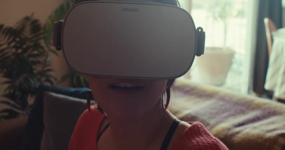 A woman wearing a vr headset sits on a couch enjoying a fun and immersive moment