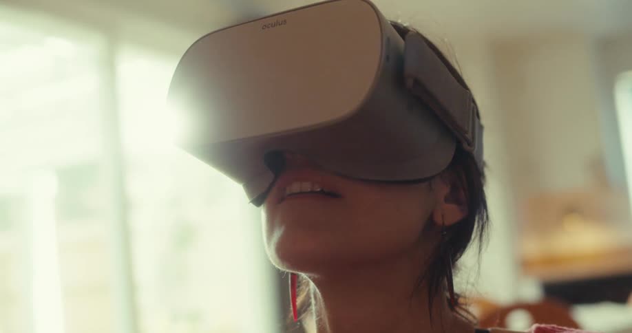 A young woman wearing a vr headset sits on a couch around midday