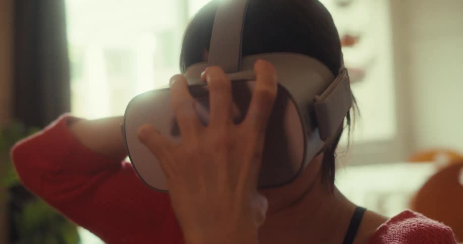 Woman sitting in her living room during the day puts on a virtual reality headset