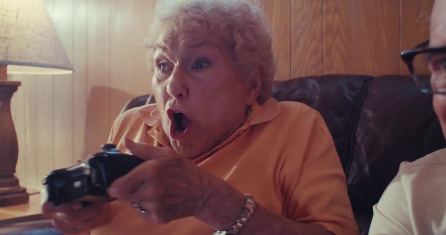 Elderly couple enthusiastically plays video games on a couch