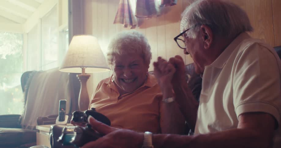 Elderly couple sitting having fun and playing video games