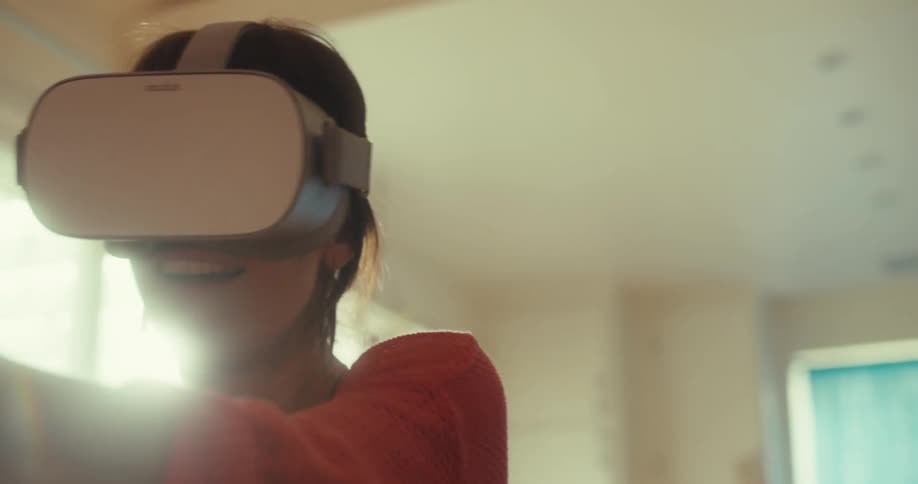 Close up of a young woman gaming with vr goggles while sitting in a living room during daytime