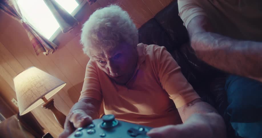 Elderly lady sitting having fun playing video game and holding wireless remote control