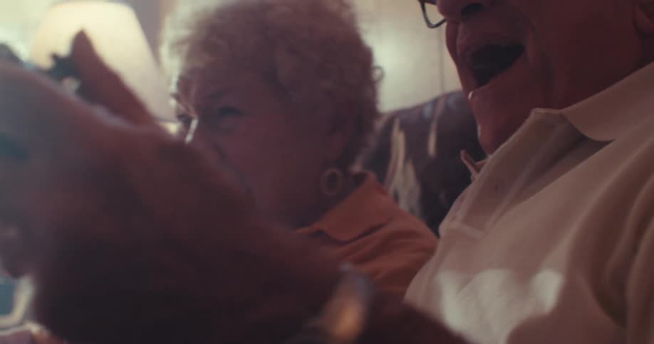 A man and woman laugh while playing video games together