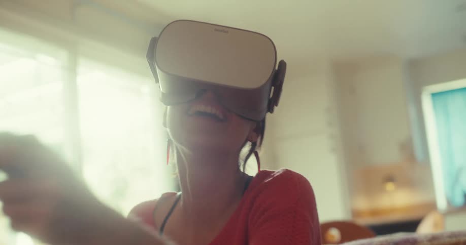 A woman wearing a vr headset plays an immersive game in a sunlit room