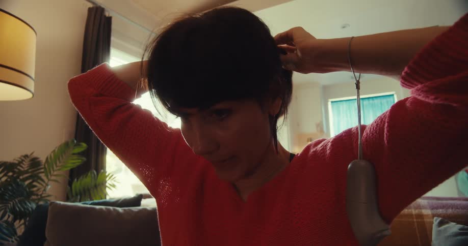 The woman puts her hair in a ponytail