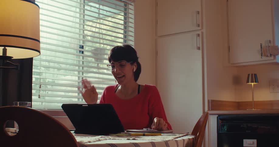 The woman talks and waves on a video call