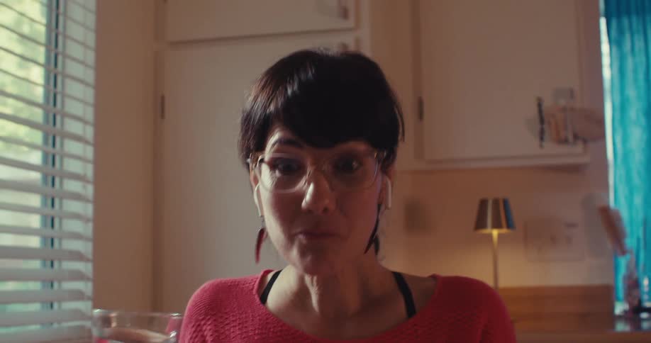 A woman is talking on a tablet and drinking water