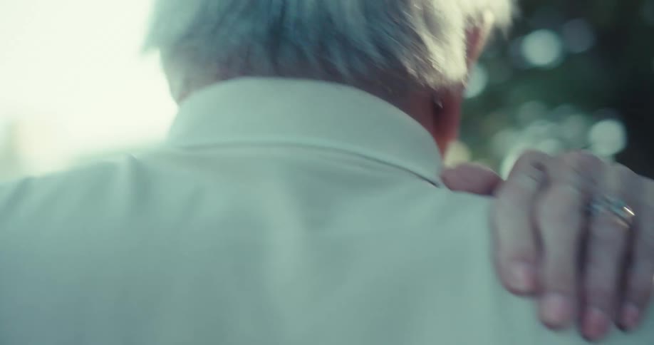 An elderly couple shares a tender moment while dancing outdoors