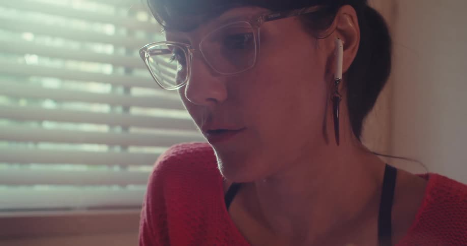A woman sitting at a table writing in a notebook and speaking