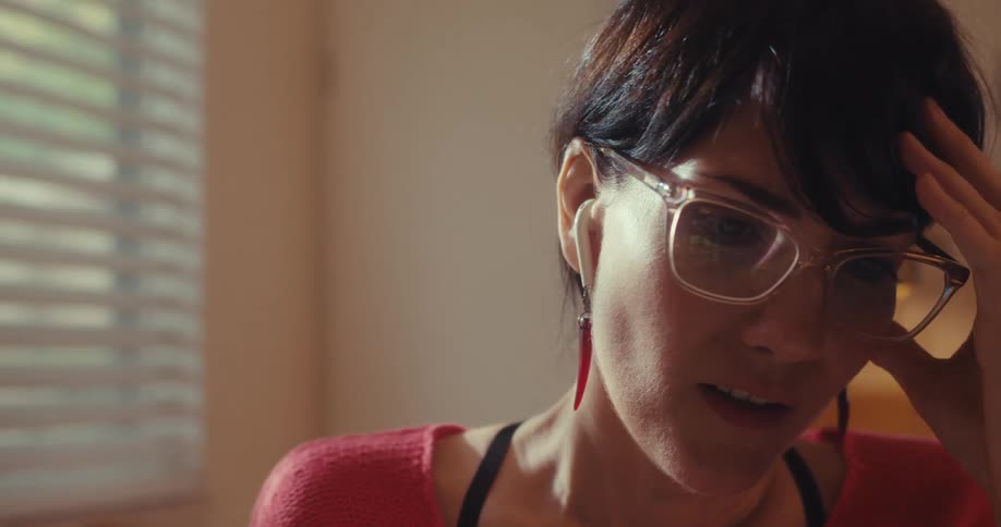 Woman with glasses sitting with her hand on her head