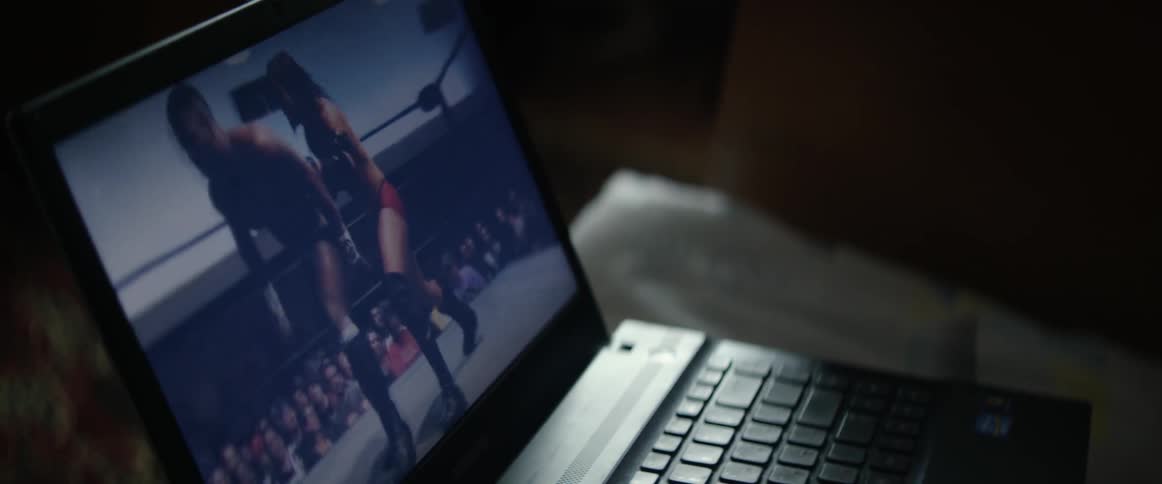 Video of two wrestlers fighting plays on a laptop screen