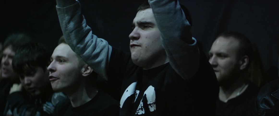 A couple men standing in a crowd yelling and moving their arms