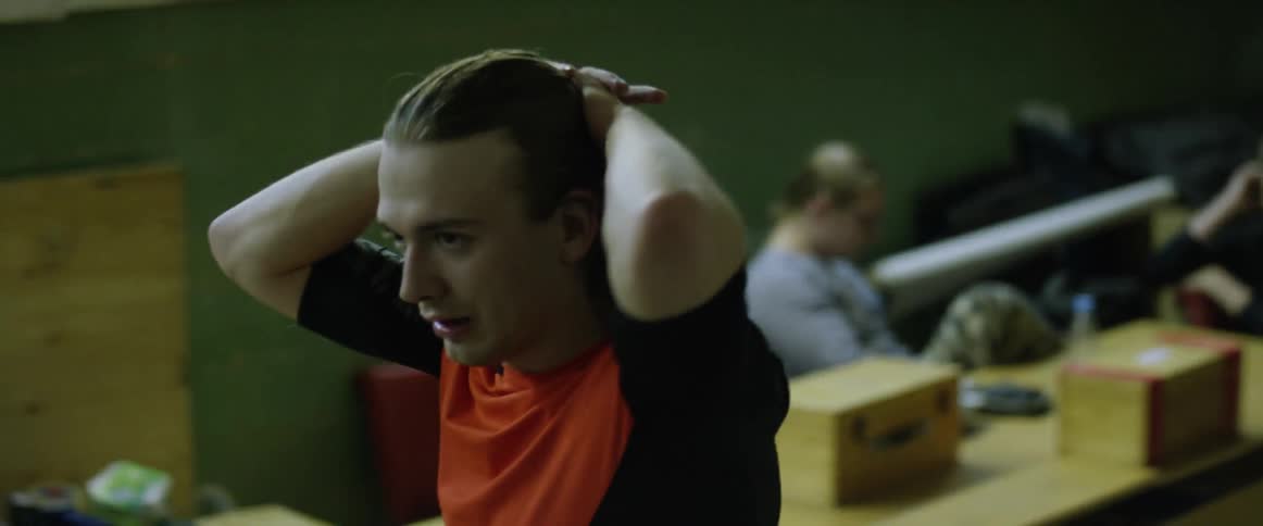 A man puts his hands behind his head as he walks in a gym