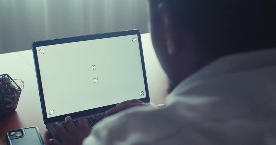 Man works on laptop showing motion tracking markers indoors