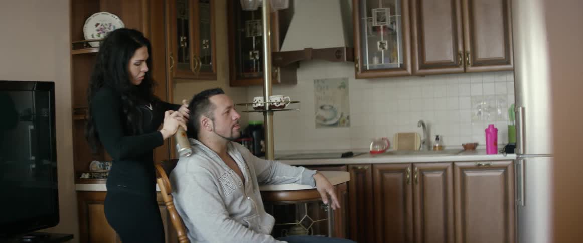 A man is sitting getting a haircut