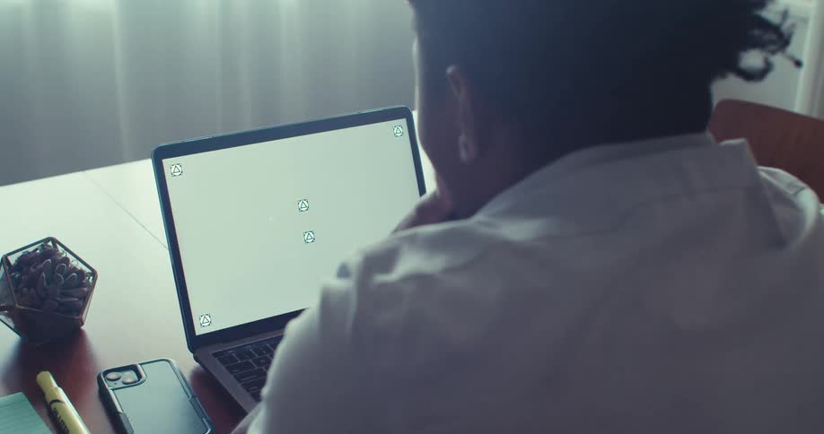 A man works on a laptop with a blank screen in a home or office setting