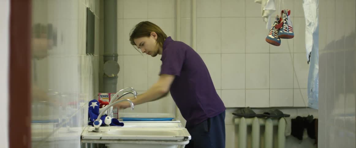 A man pours granulated soap into a sink then washes clothing items