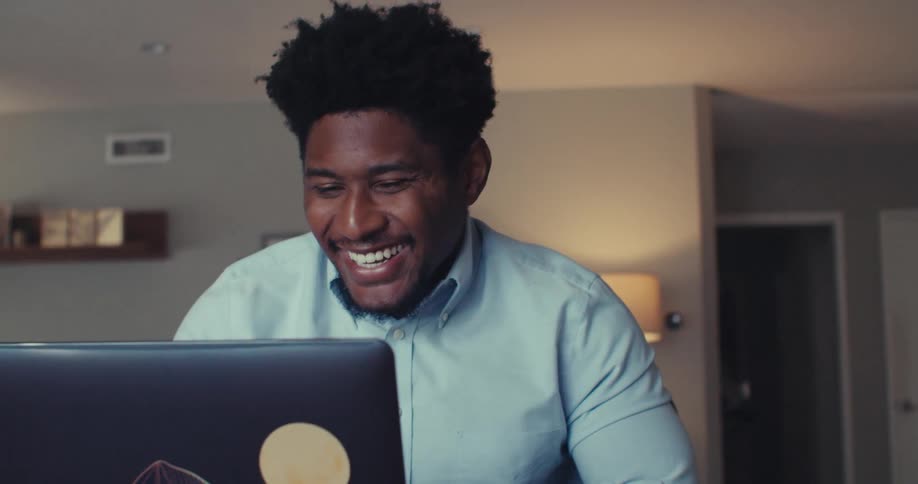 A smiling man gestures expressively while video chatting on a laptop at home