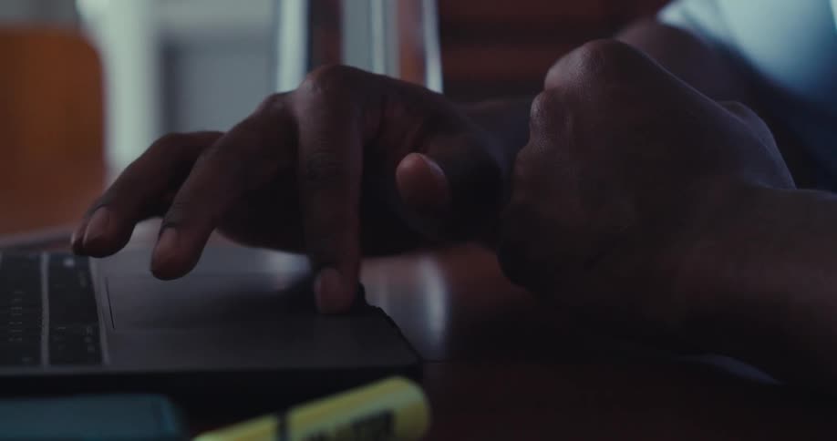The man is using the track pad on his laptop