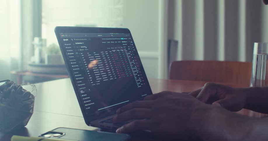 Person reviewing printed data while working on a laptop at a desk
