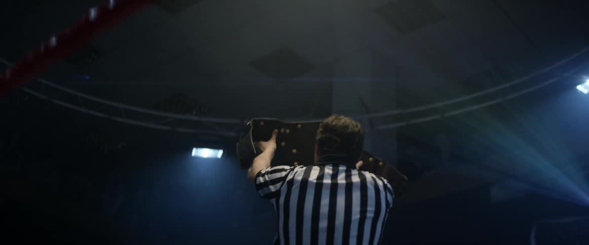Referee holding up belt in boxing ring