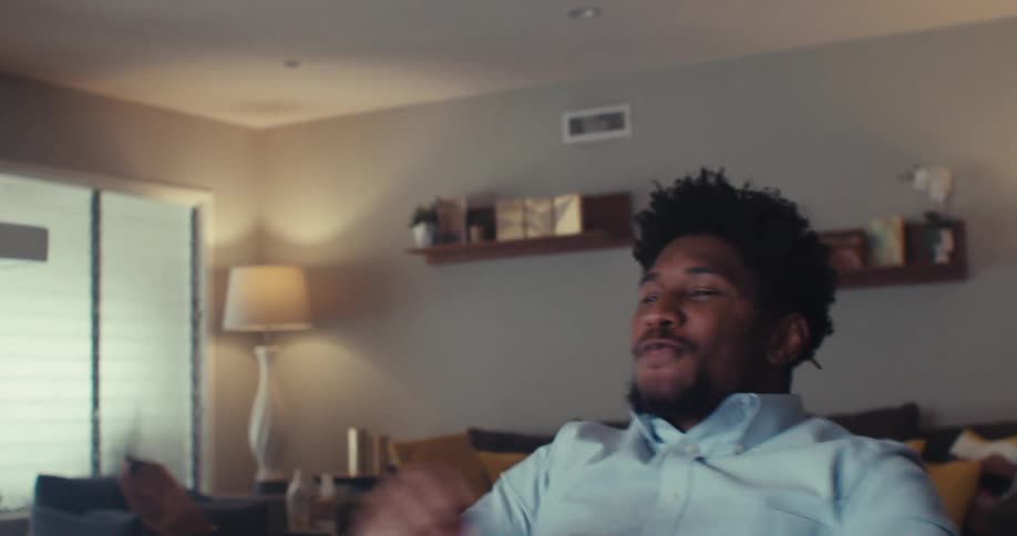 A man cheers and throws his hands up at home