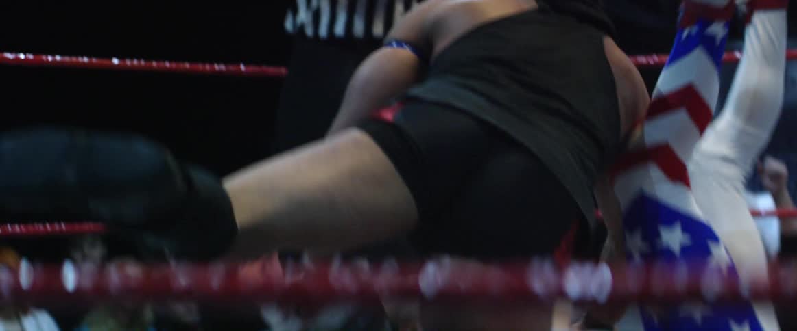 Wrestlers are having a match with a referee watching