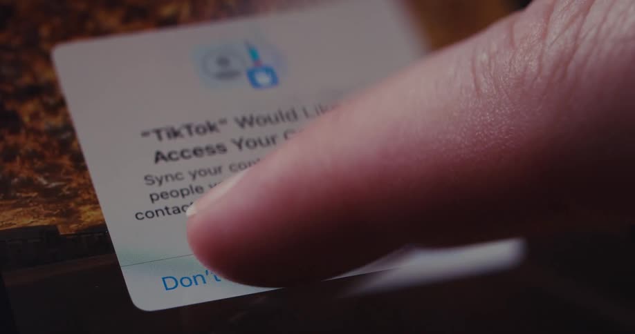 A finger presses a button on a phone screen