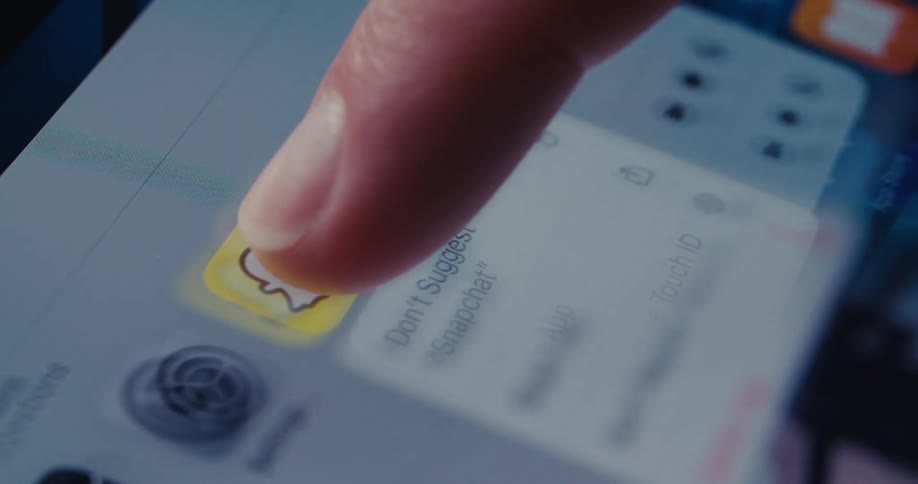 A finger presses the snapchat icon