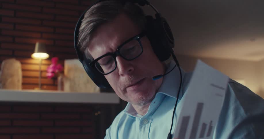 A man in an online meeting giving a presentation and showing a paper with charts