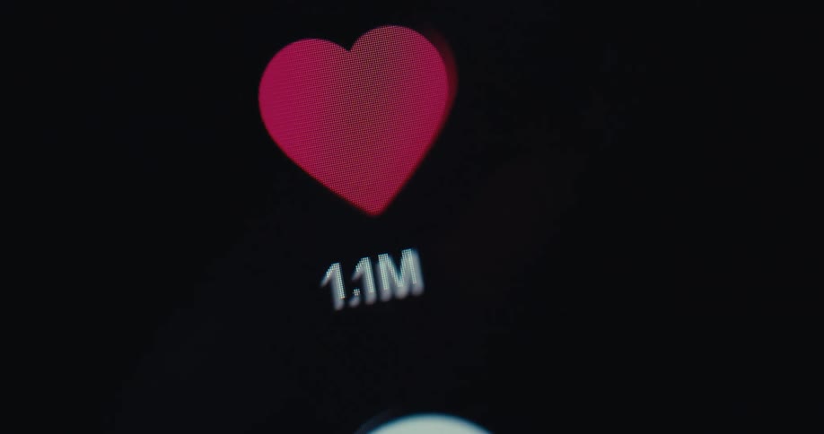 Close up of a device screen as a person taps the like button on a social media interface