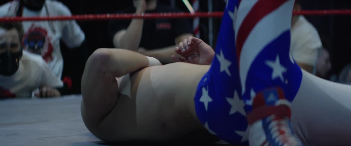 A wrestler grimacing in pain lies on the mat