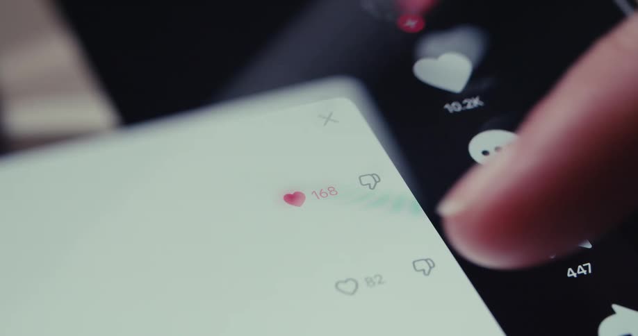 A persons finger clicking on a cell phone screen on a heart symbol turning it red