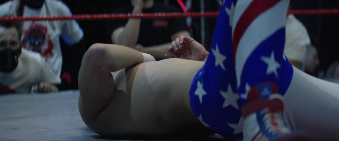 A wrestler lies on the mat in pain