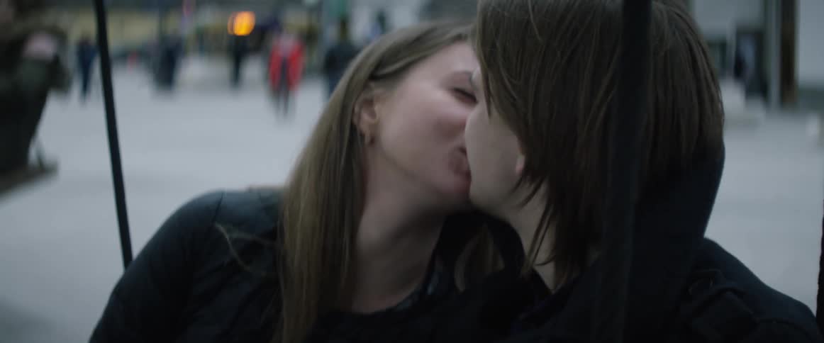 A woman kisses the man sitting beside her