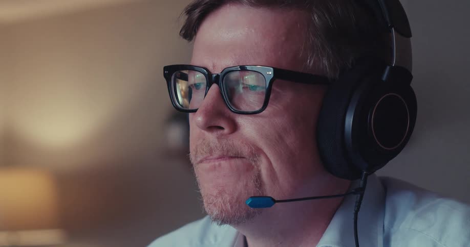 A man works at a laptop while wearing headphones appearing focused and analytical