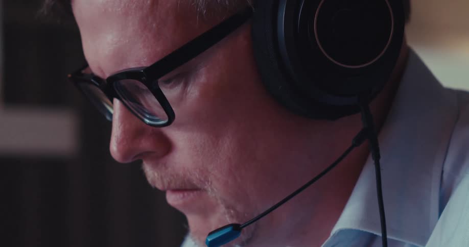Close up of a man wearing headphones typing on a computer keyboard