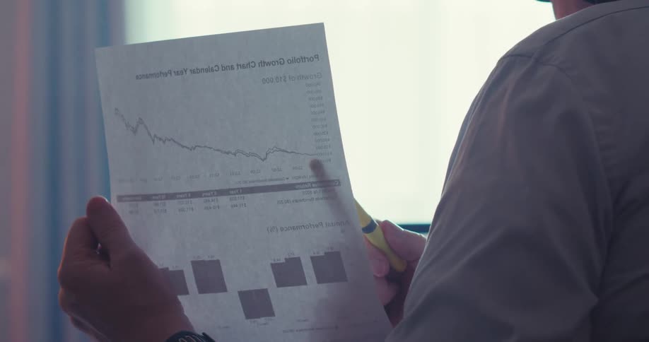 Man analyzes a stock performance chart while speaking on a headset