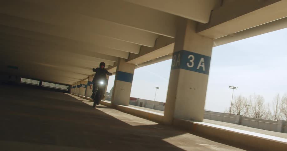 A man does a wheelie in the parking garage