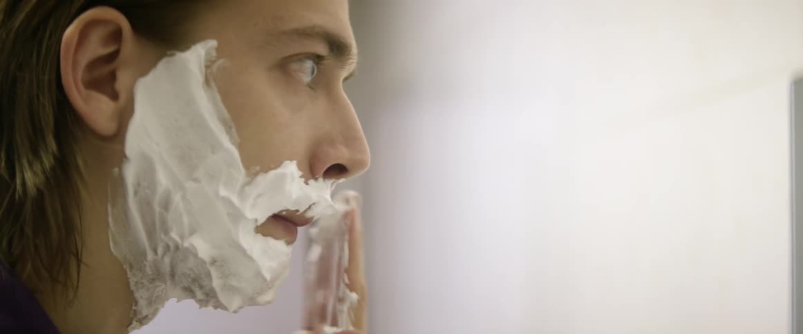 A man is applying shaving cream to his face