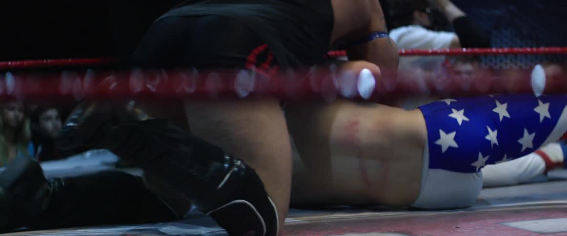 A couple of men wrestling in a ring with people watching