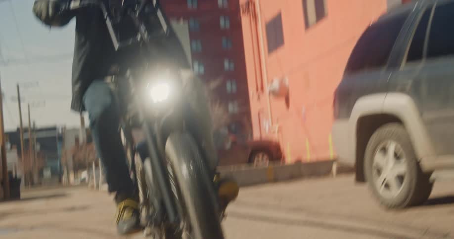 A man rides his moped-style electric bike through a city back alley