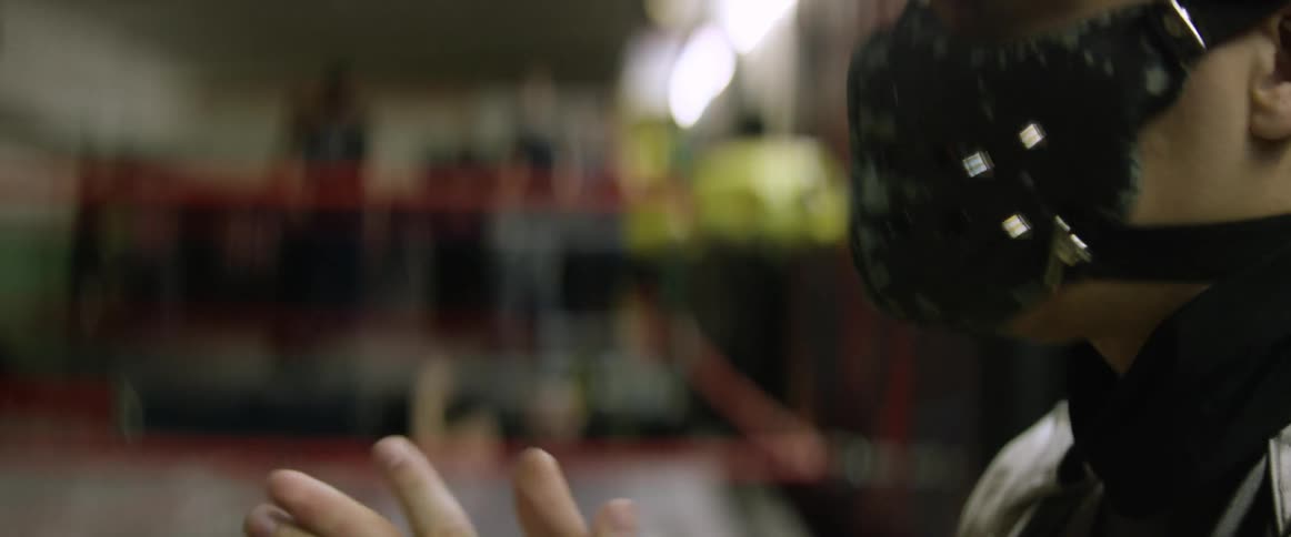 A man puts on and adjusts a wrestler's mask